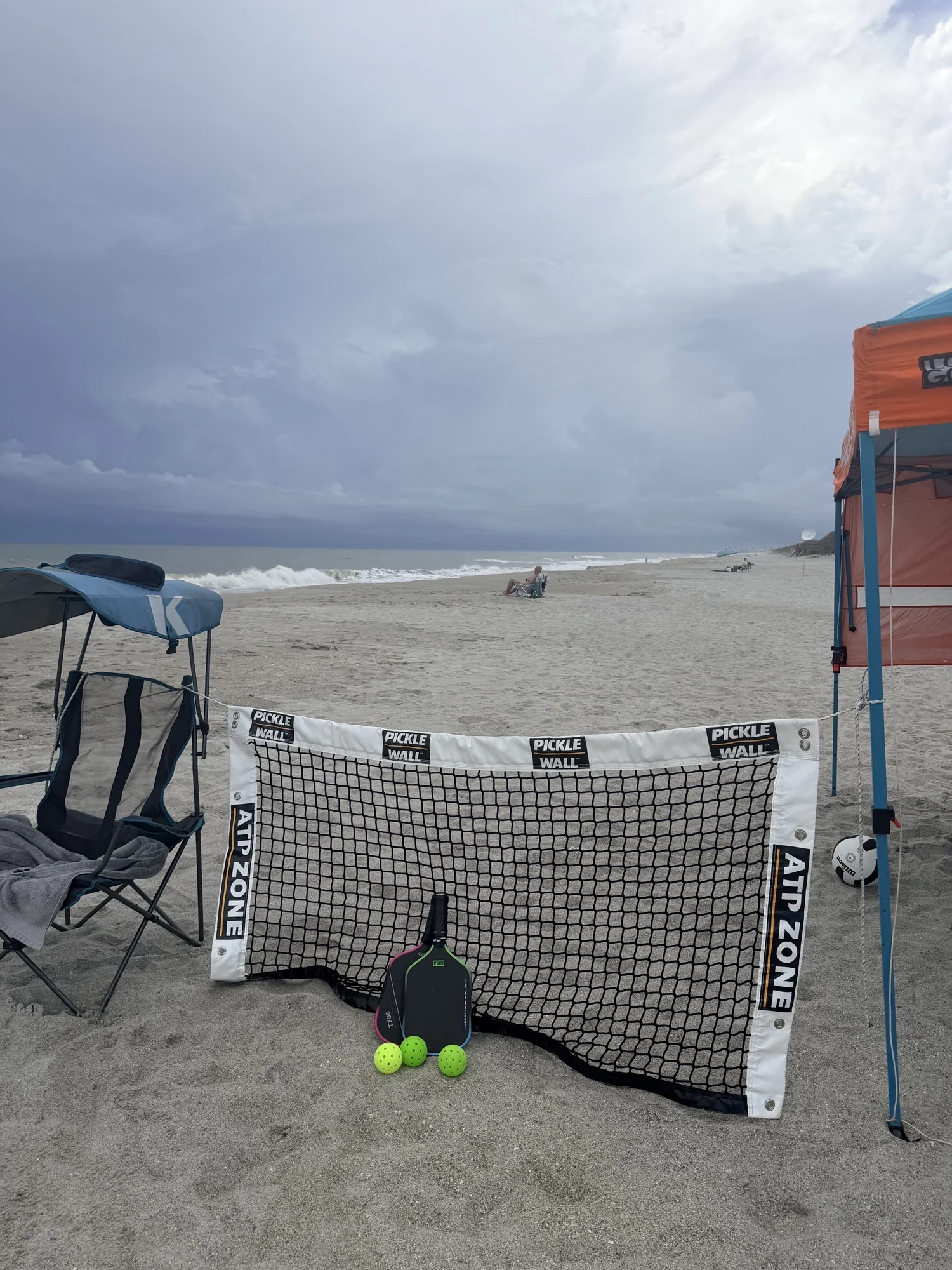 Pickle Wall portable pickleball training net set up on a Florida beach with a paddle and pickleballs, demonstrating the Anywhere. Anytime. pickleball lifestyle.